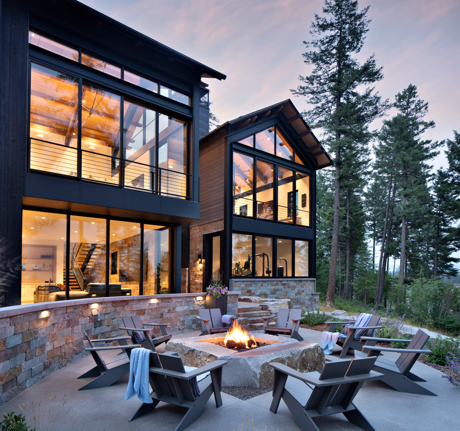 A large house with a fire pit in the backyard, surrounded by grass and trees, creating a cozy outdoor space.