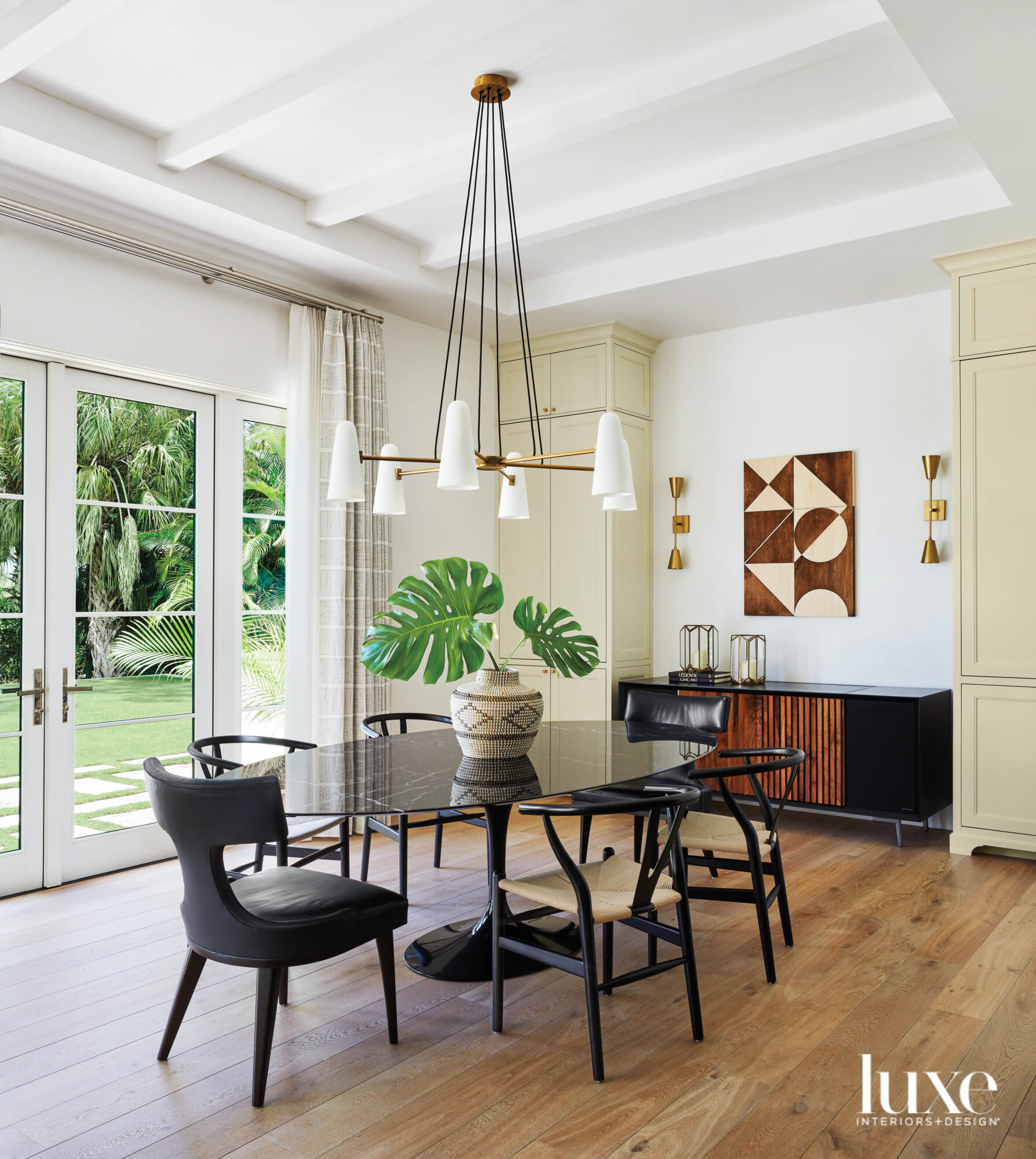 dining area with oval table, black chairs, chandelier and wood cabinet