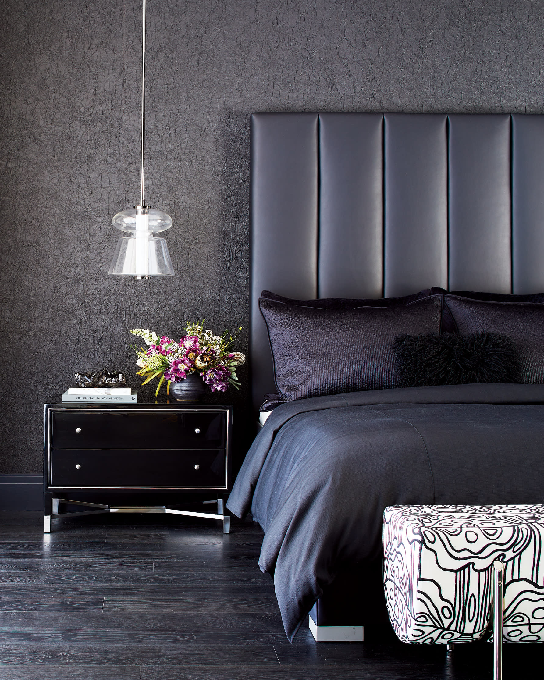 black bedroom with textured wallcovering, leather headboard and black nightstand 