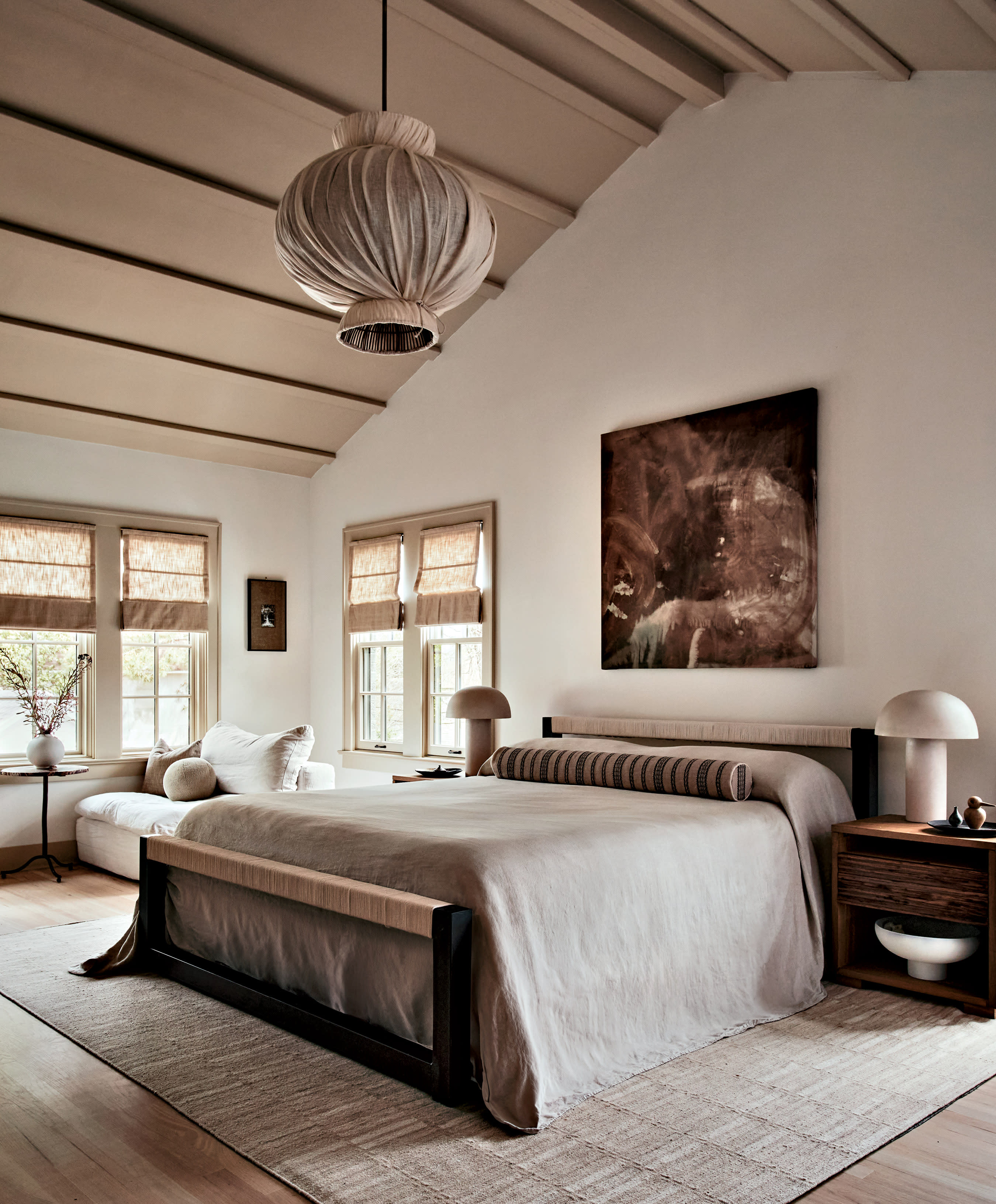 A bed in the center of a bedroom with nightstands and a domed ceiling with a hanging light fixture.