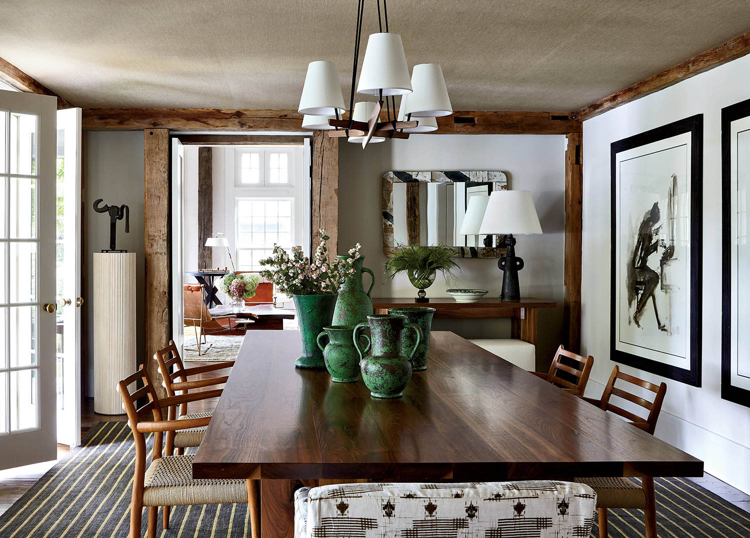A dining table decorated with green jugs and vases, surrounded by chairs and artwork on the walls.