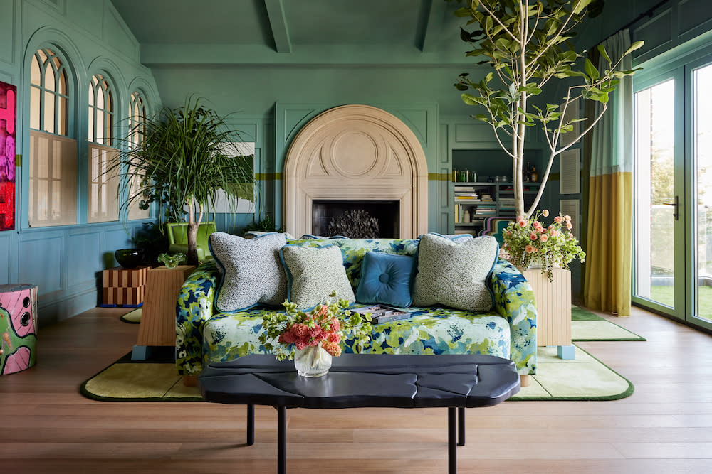 A cozy living room featuring a green couch, European oak flooring and a large indoor plant, creating a vibrant and inviting atmosphere.