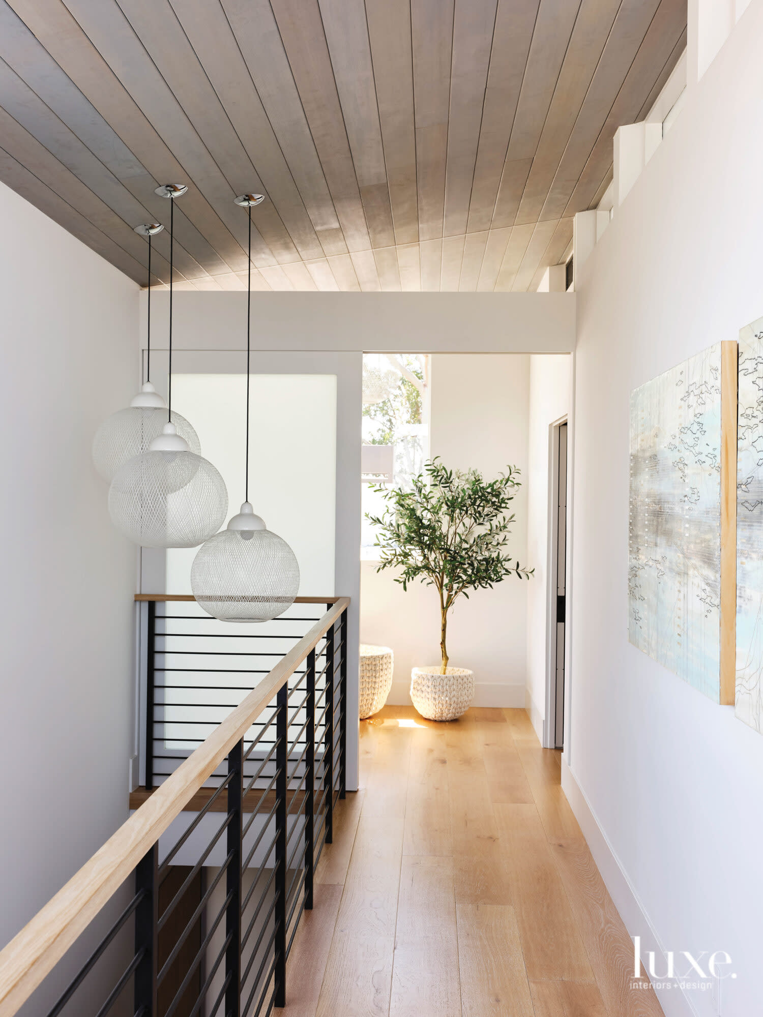 An upper hall is filled with light and sculptural light fixtures.