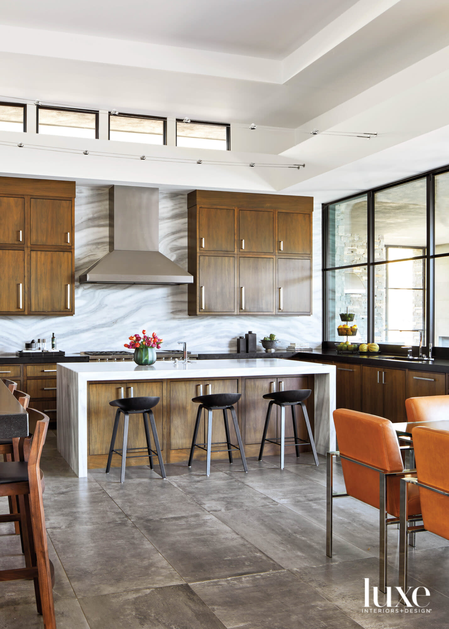 A minimalist kitchen with marble backsplash and black counter stools