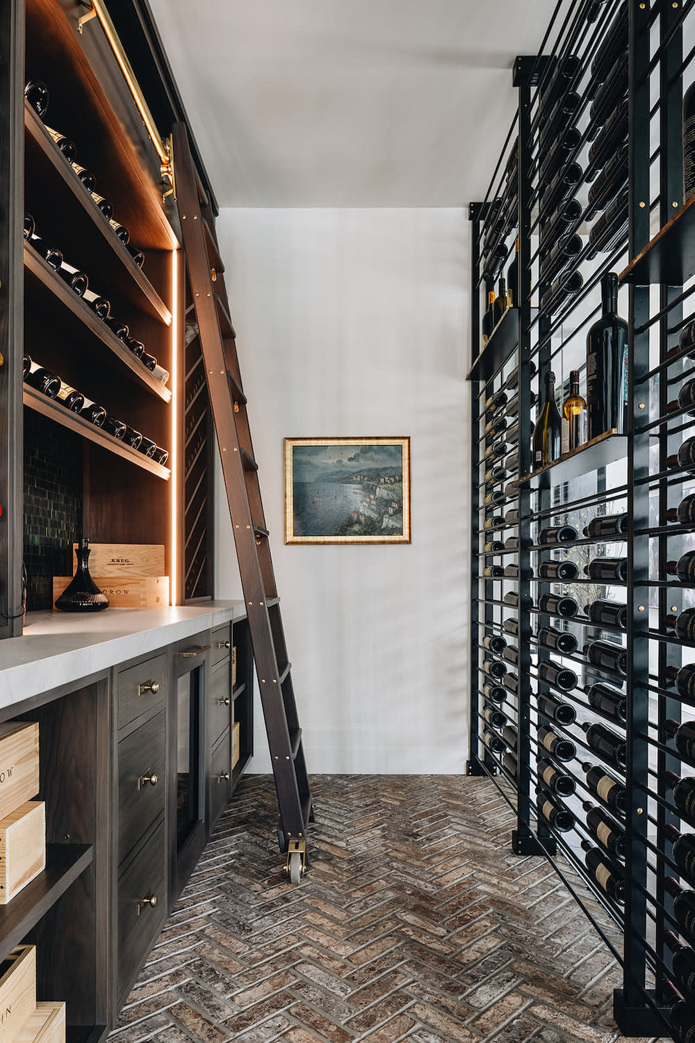 This wine room with black racks to display wine bottles, dark cabinetry, and brick floor in chevron pattern.