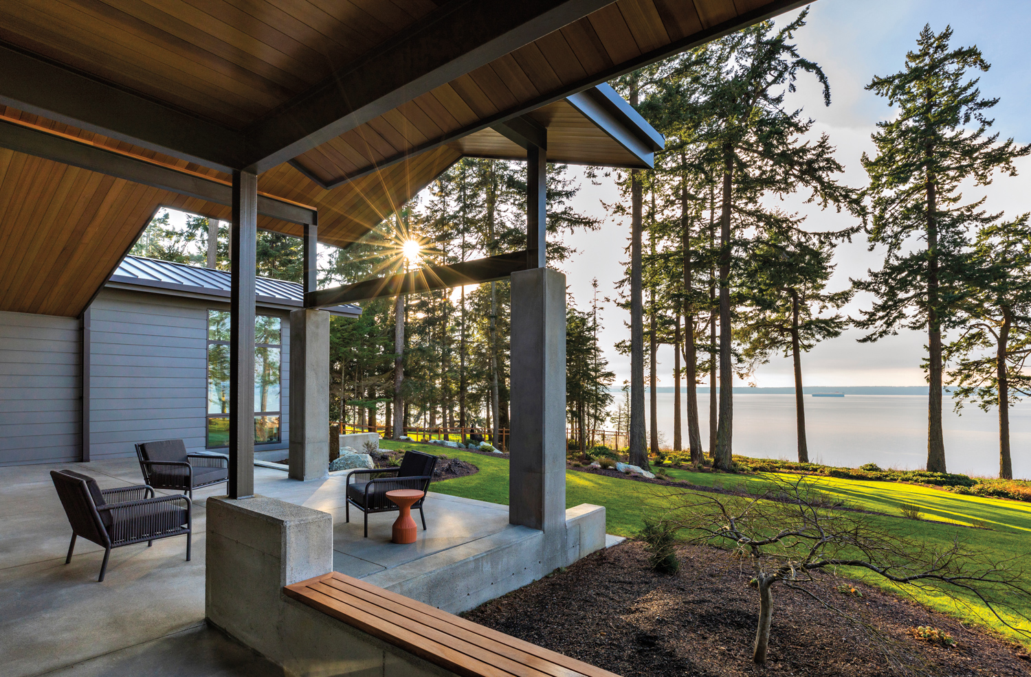 An outdoor seating area has views of the water and trees.