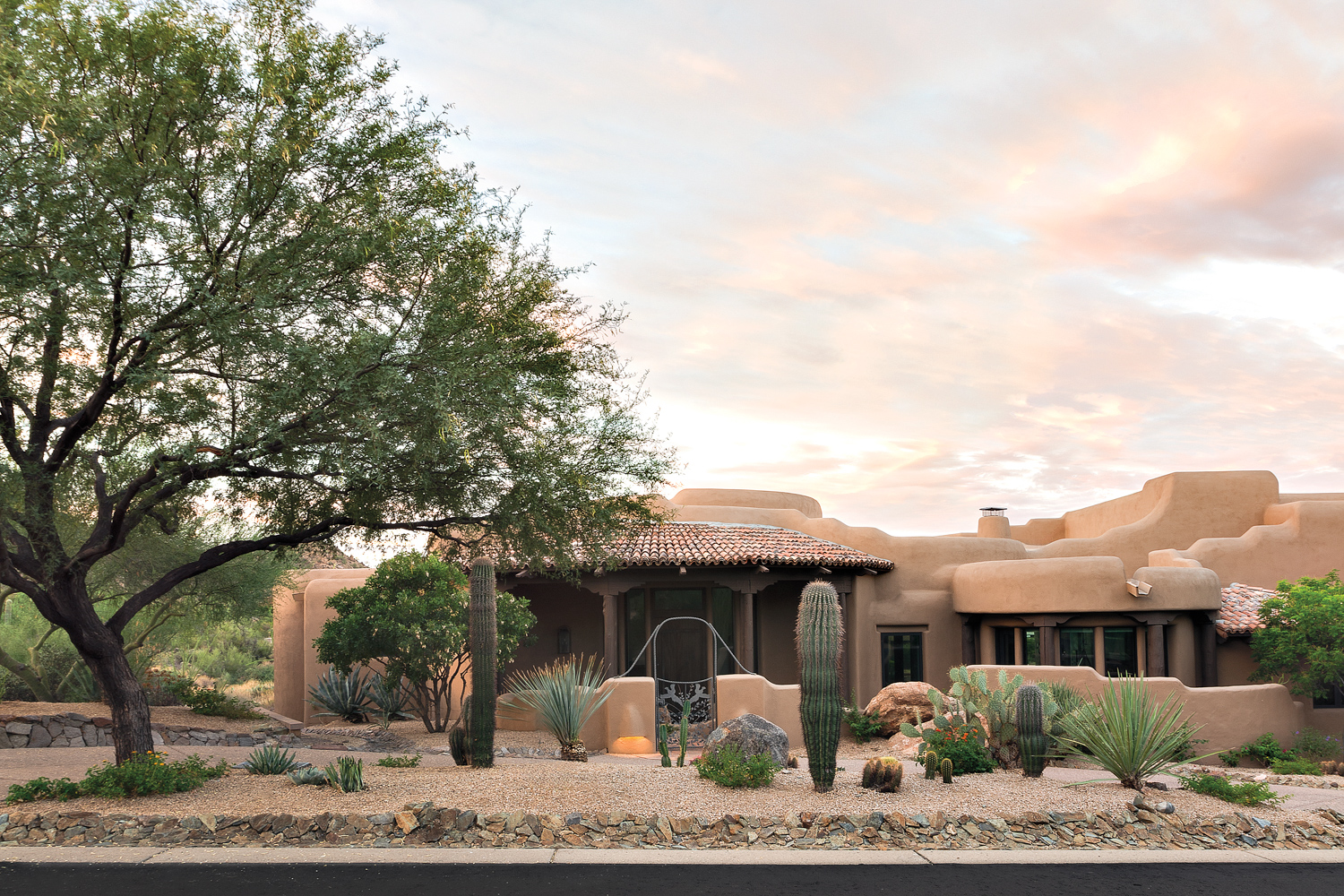 front of pueblo style home with curved exterior and cacti in front yard