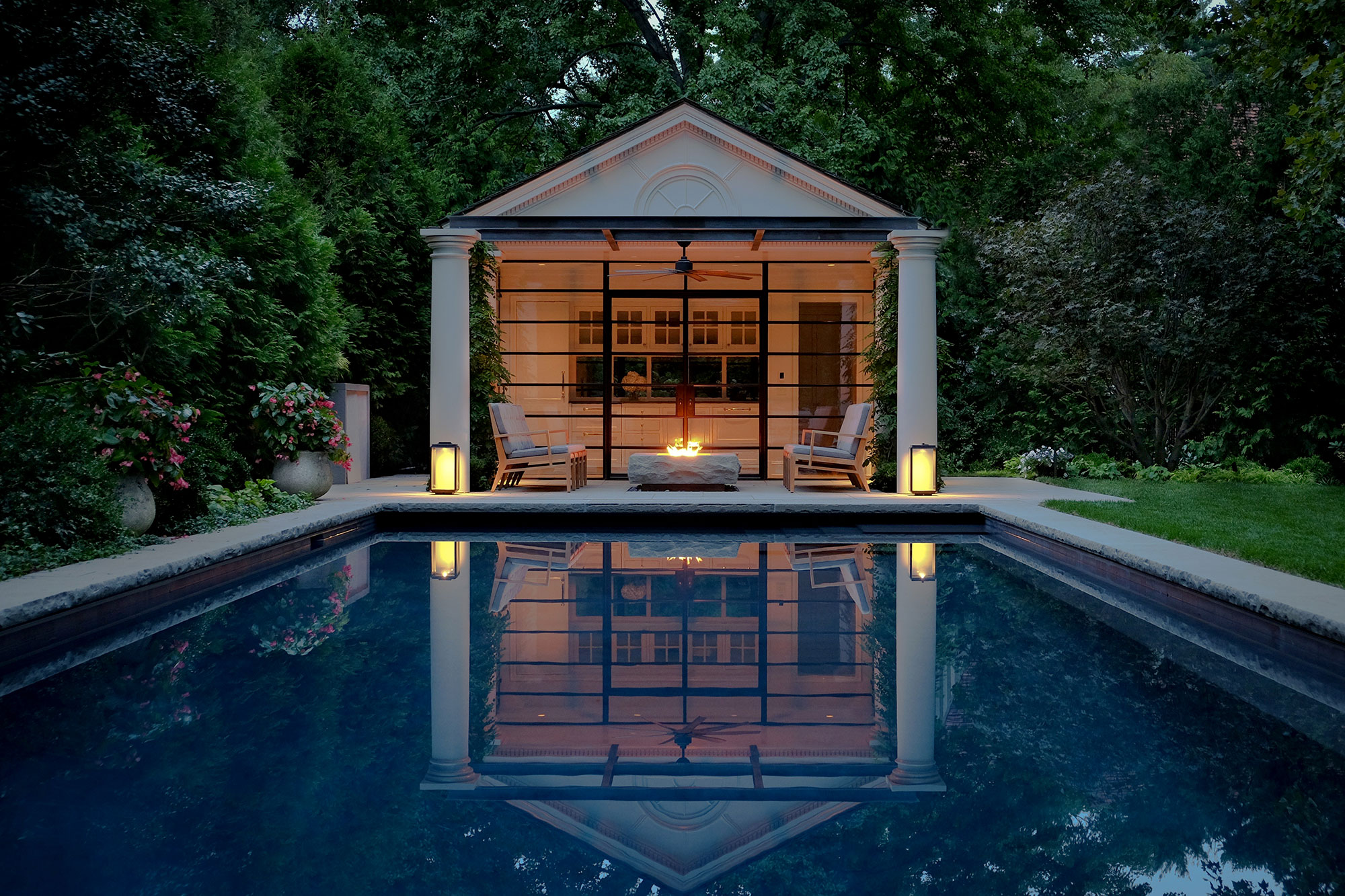 Swimming pool and poorhouse at evening, lit by lanterns and a fire pit