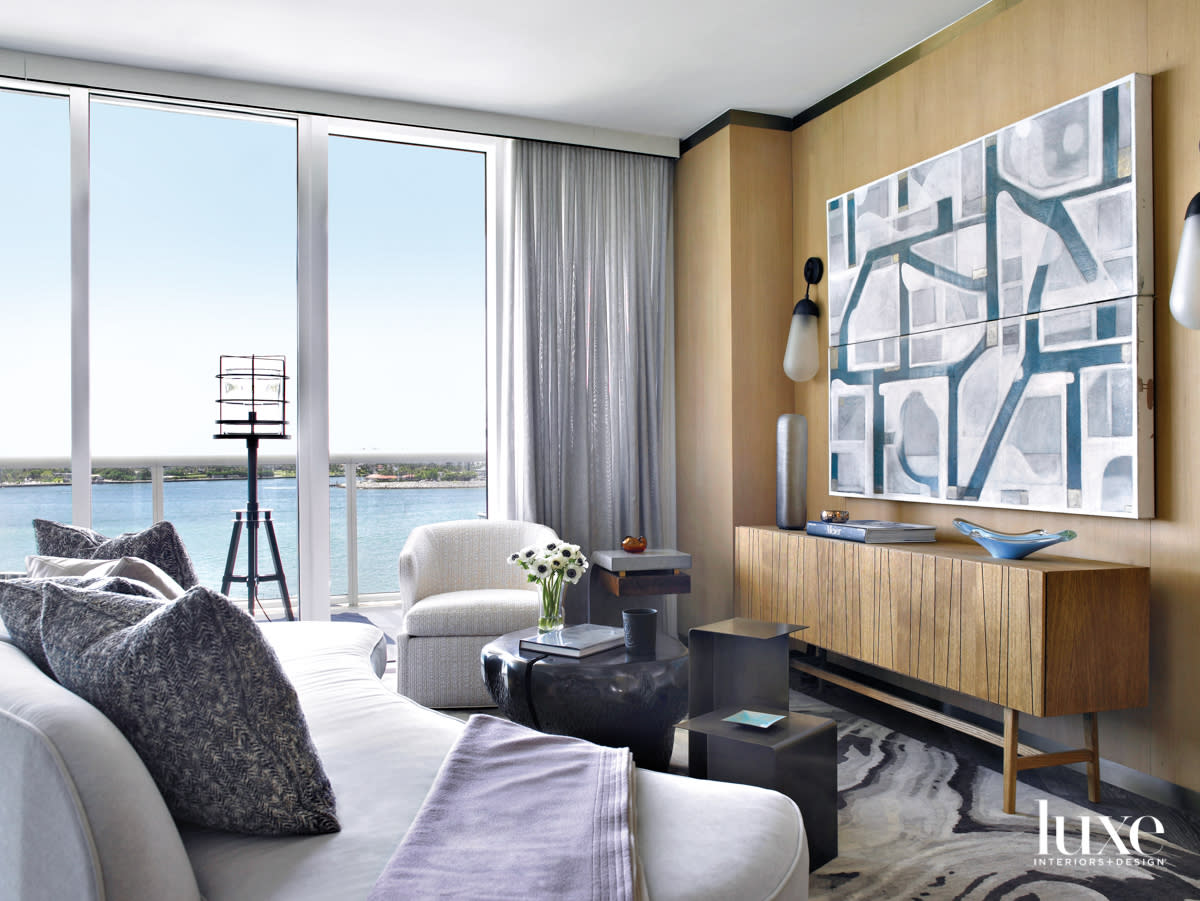 living area with curvy sofa, floor lamp, wood wall paneling and diptych