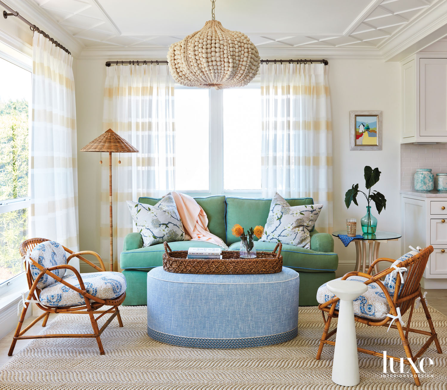 morning room with beaded chandelier, blue ottoman, green sofa, rattan floor lamp and armchairs