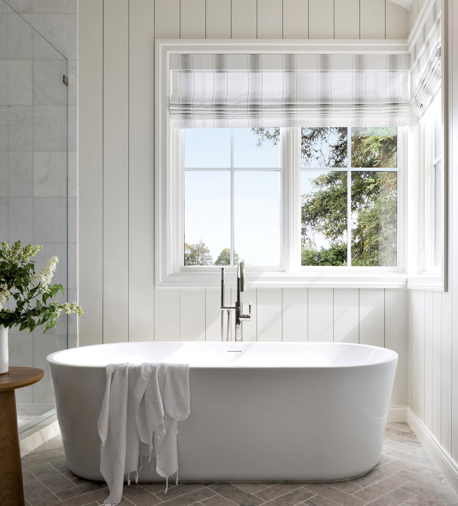 classic primary bathroom with white paneled walls and a freestanding tub