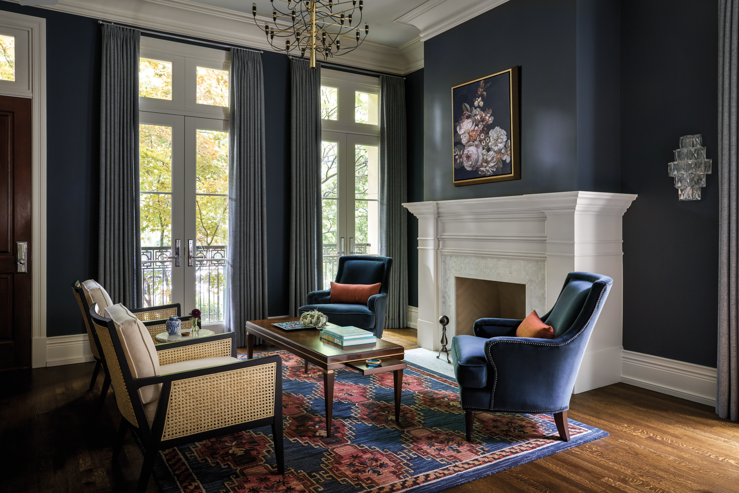 Living room with navy blue walls, white moldings and fireplace and blue velvet armchairs