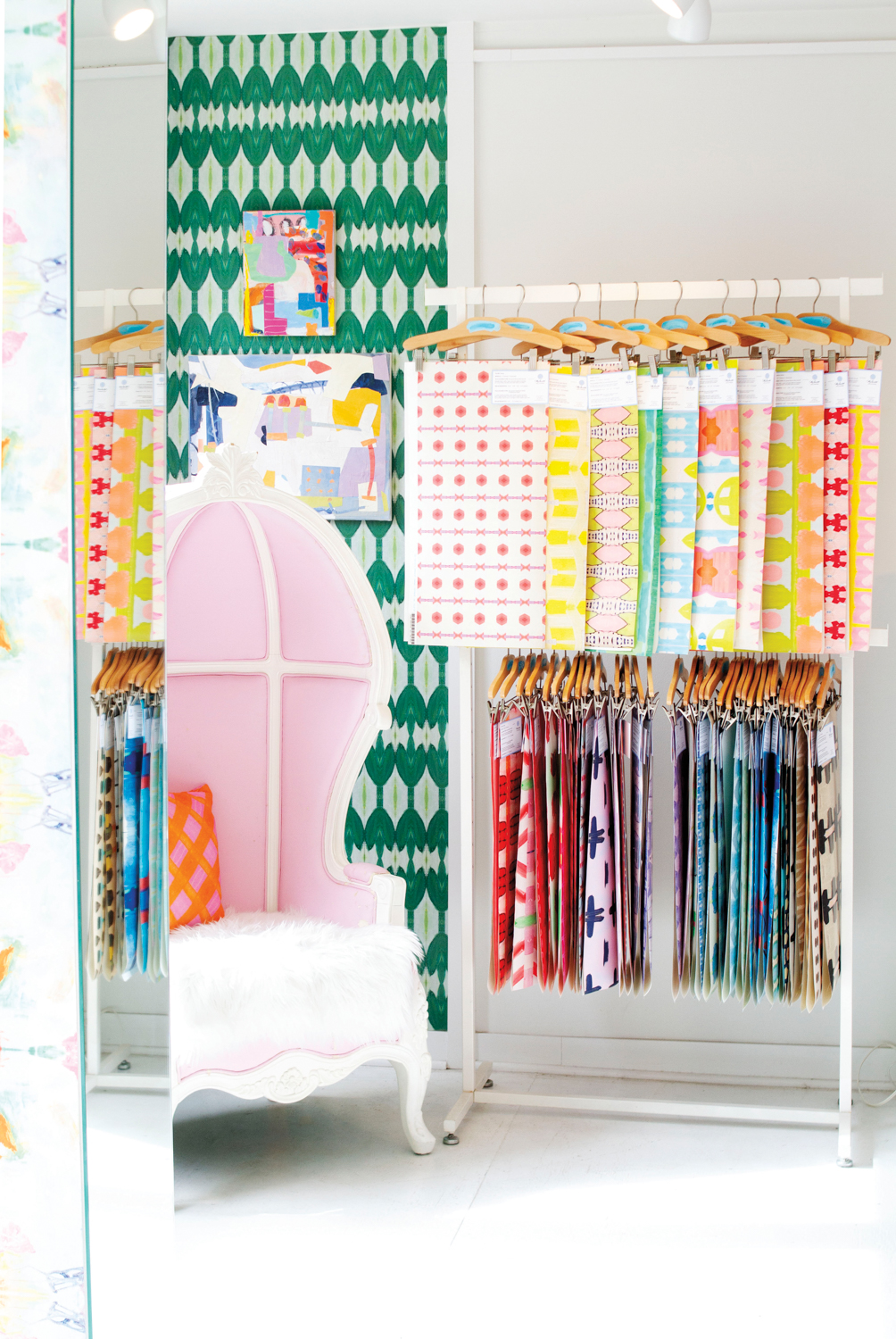 Pink-and-white chair in front of several colorful wallpaper samples.