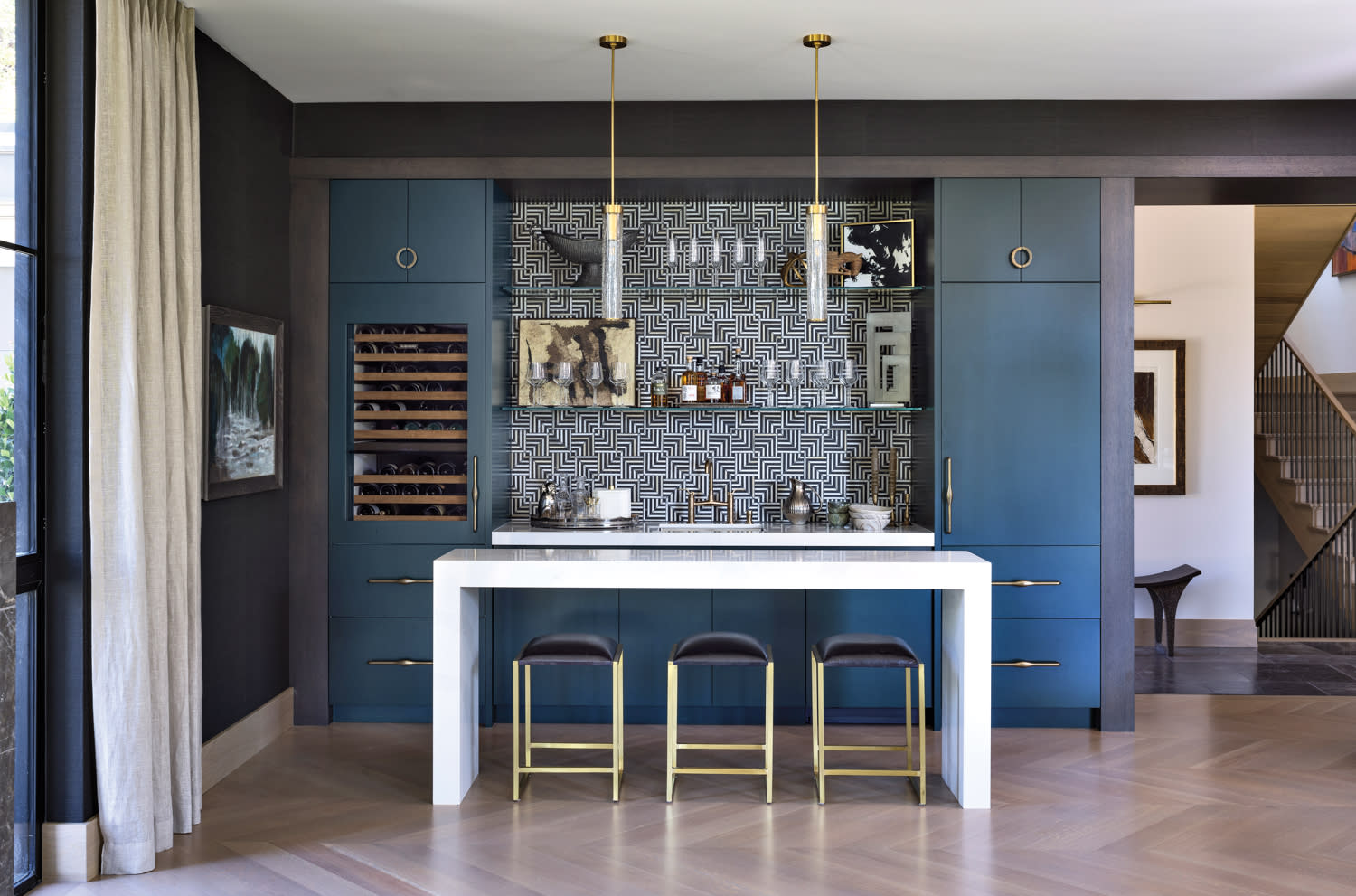 bar in living room with quartz waterfall table, black stools, cylindrical pendants and graphic backsplash