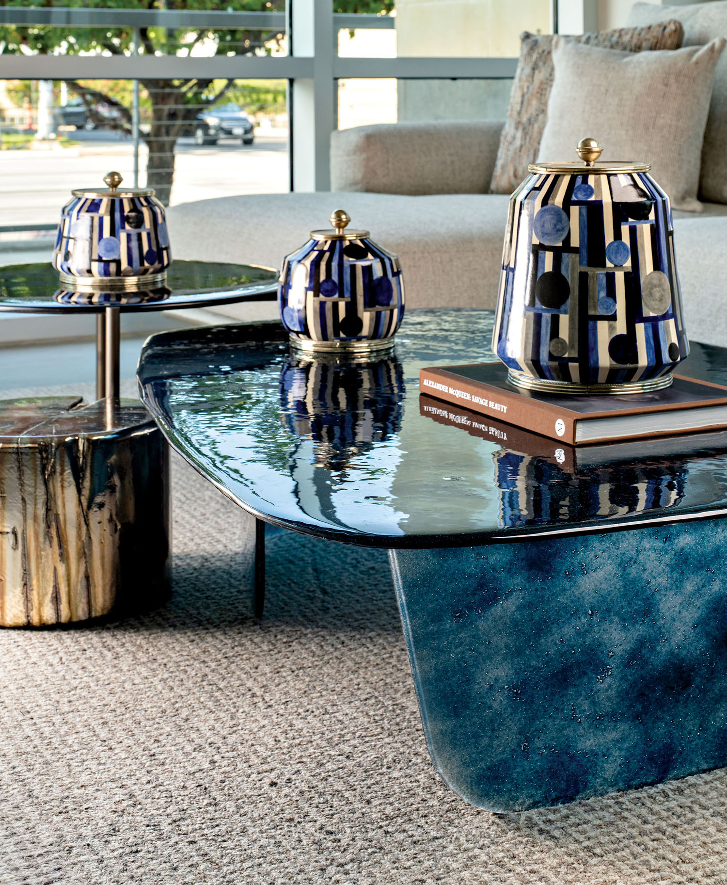 Two angular tables placed next to one another with books and blue-and-gold ceramics sitting on top.