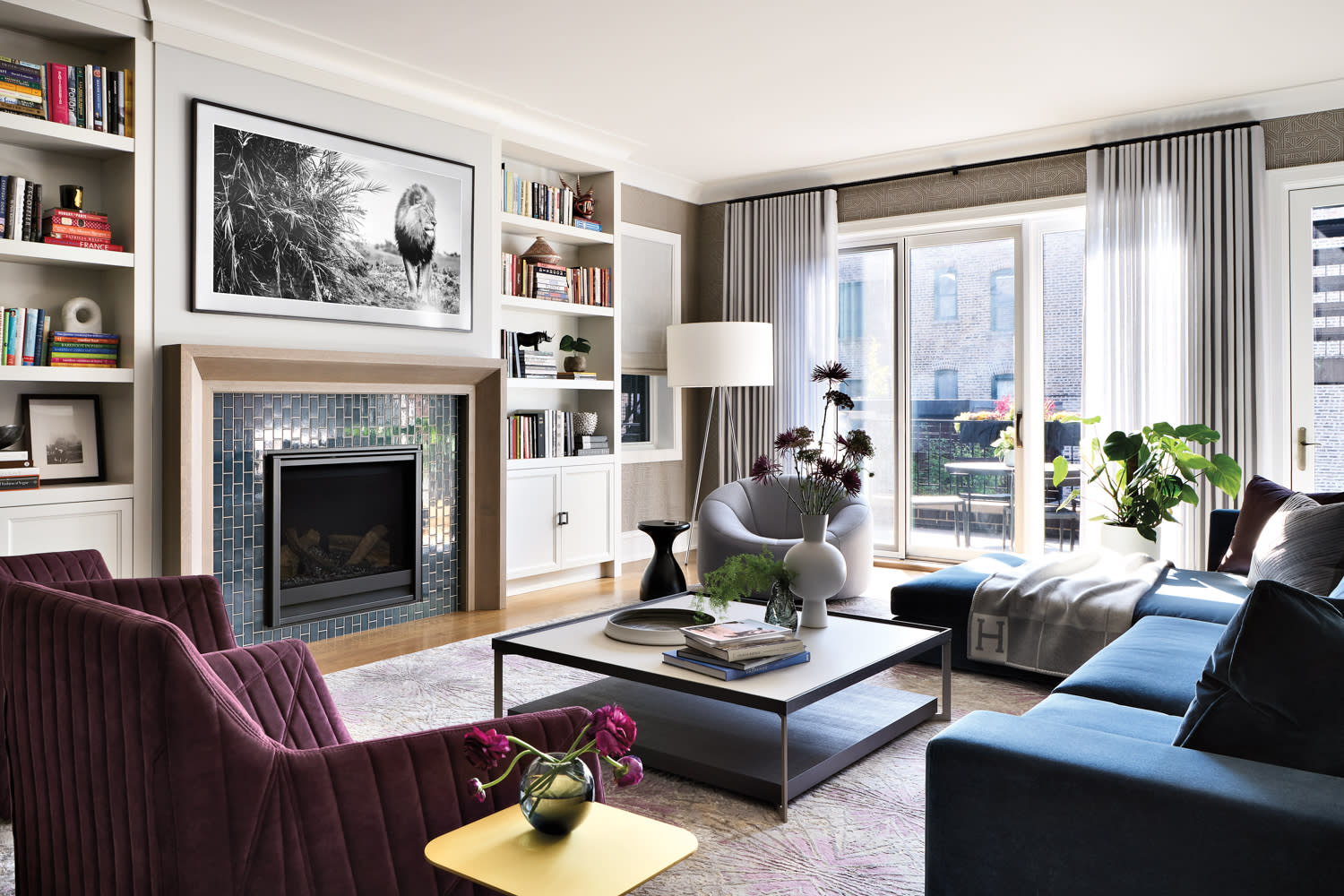 Family room with teal fireplace, lion photo, a blue sectional, plum armchairs and a gray swivel chair