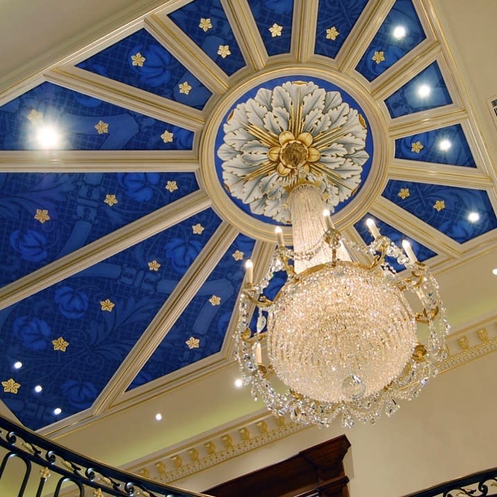 Intricate patterns of carved wood and delicate plasterwork adorn the ceiling, creating a visually stunning display.