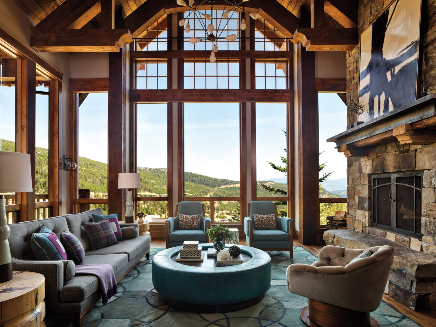 Large wall window dominates the living room with a circular blue coffee table and matching blue armchairs.