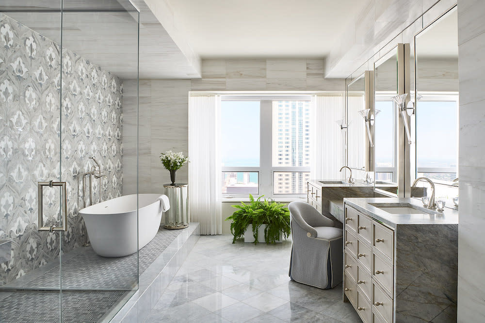 Primary bath with beautiful views from the double window. Standalone white tub and glass enclosed shower. Decorative tile from floor to ceiling.