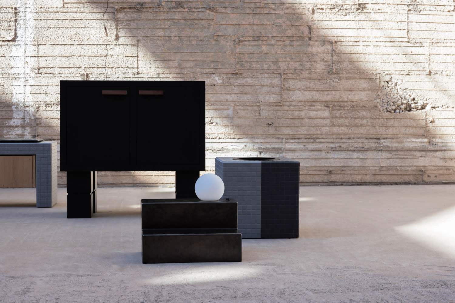 Gray bench, black vanity and a black nightstand lamp in front of a gray wall