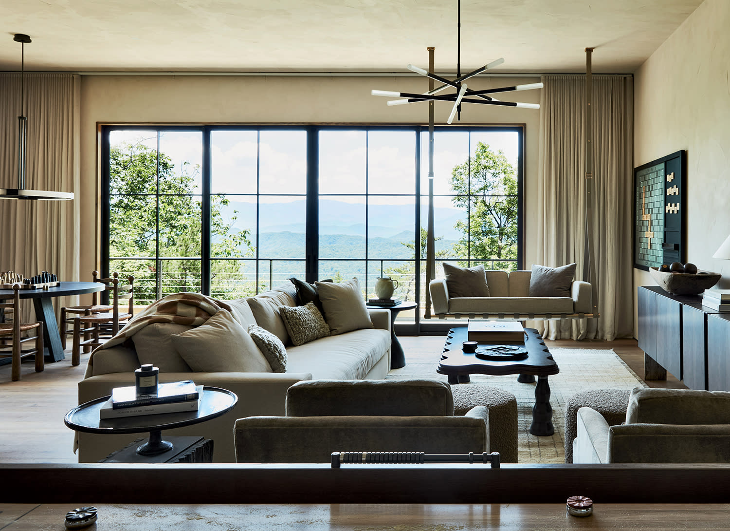 Couches in a U shape surrounding a table near a large window, with another table nearby set up with a chess board.