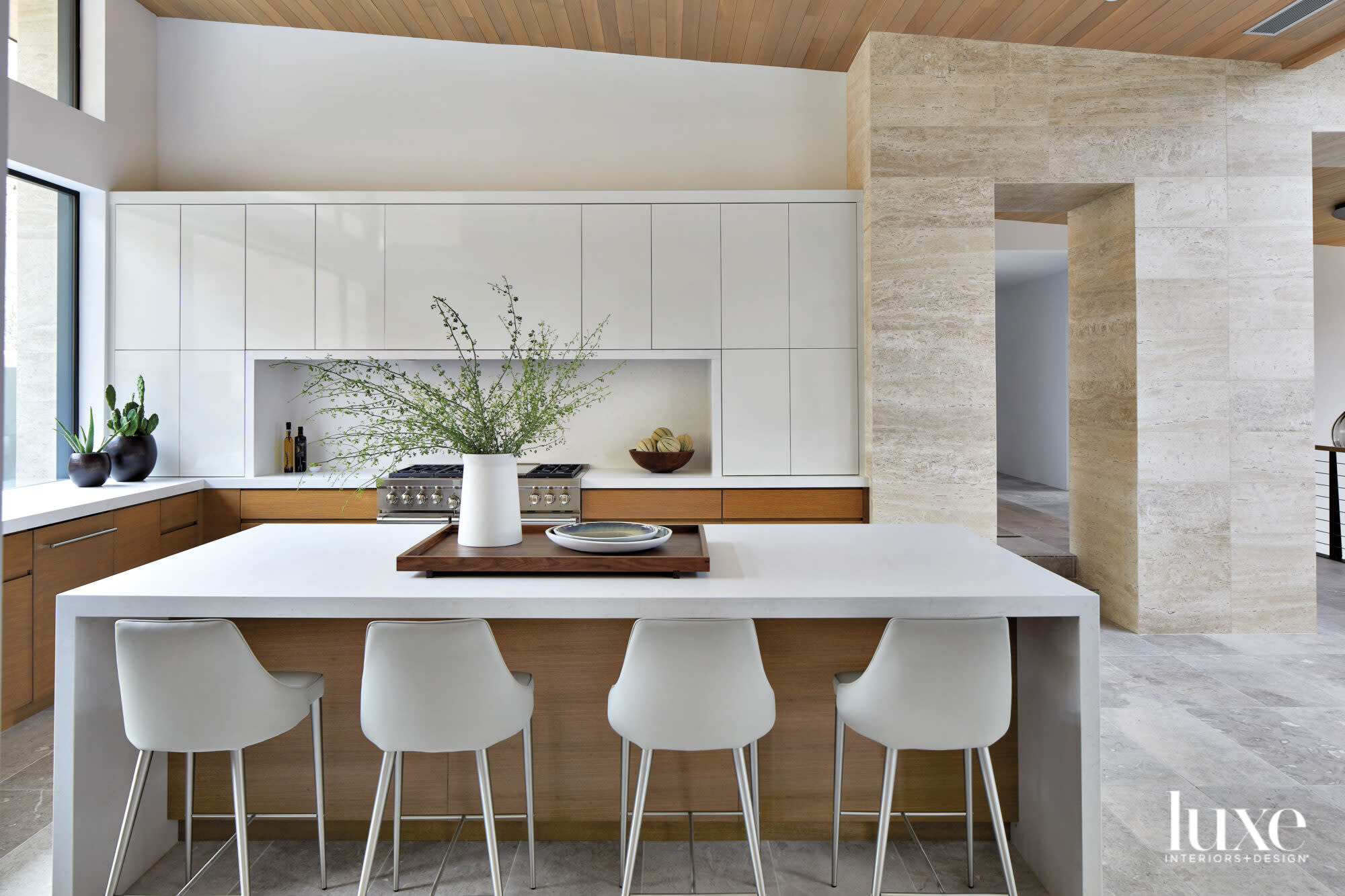 A minimalist kitchen with white top cabinetry, a white island and white counter stools