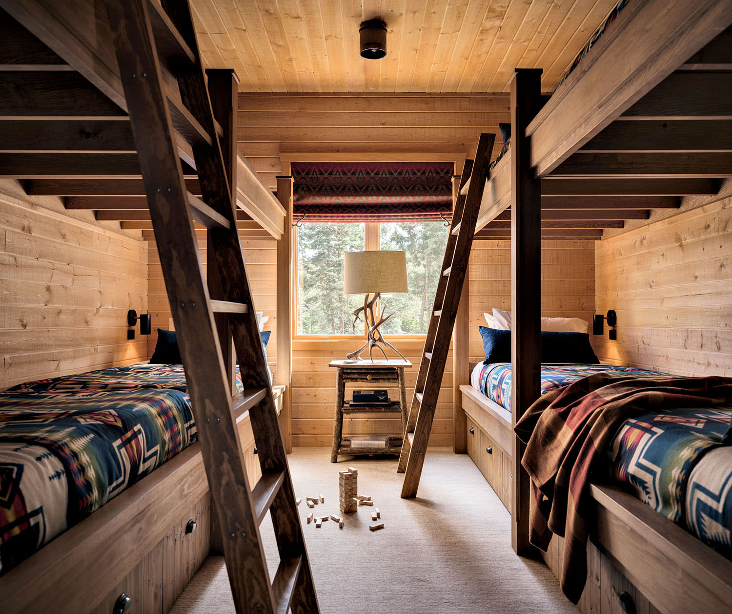 Two sets of bunkbeds line opposite walls of a room with matching ladders and printed bedspreads