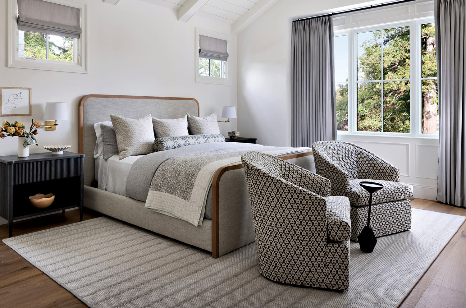 white contemporary bedroom with a gray bed behind two gray armchairs