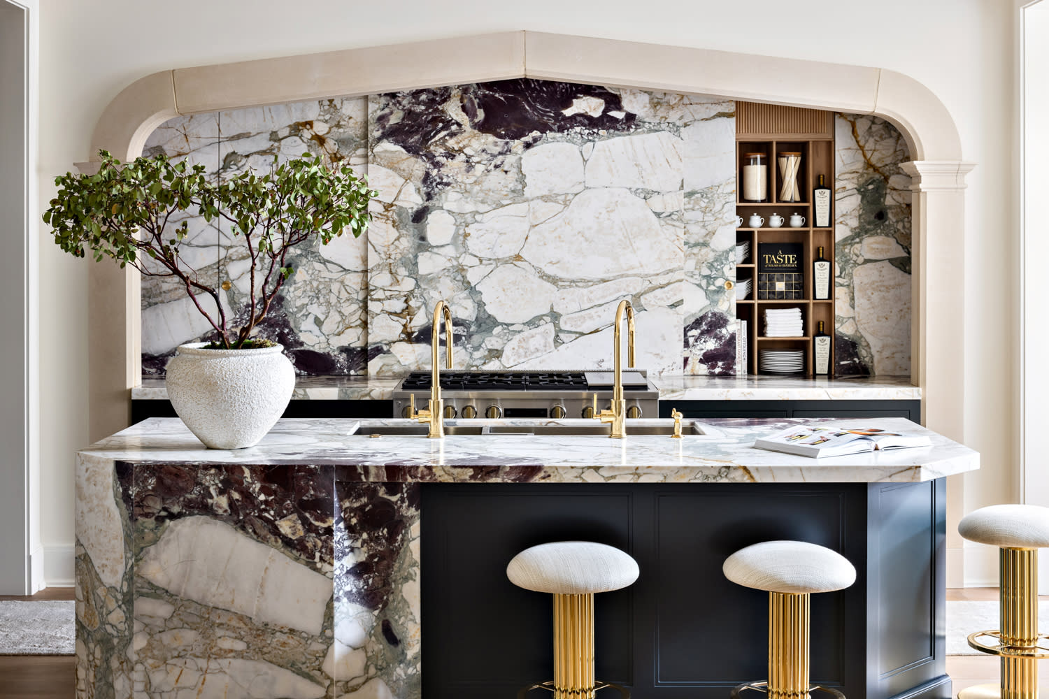 dramatic marble lines the countertops and backsplash in this modern kitchen