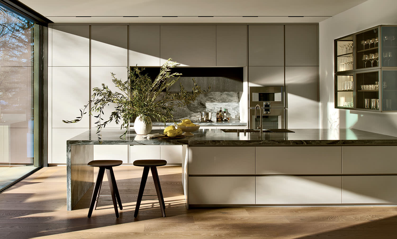 Modern kitchen bathed in warm light, featuring sleek cabinetry and a large island with two stools