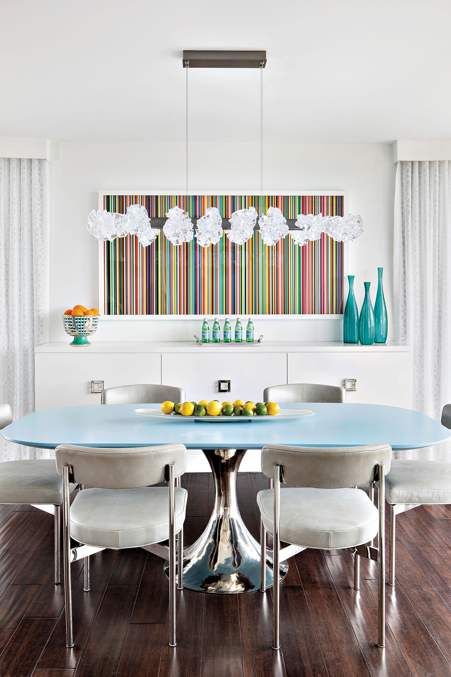 coastal-inspired dining room with a blue table and mutlicolor artwork on the wall
