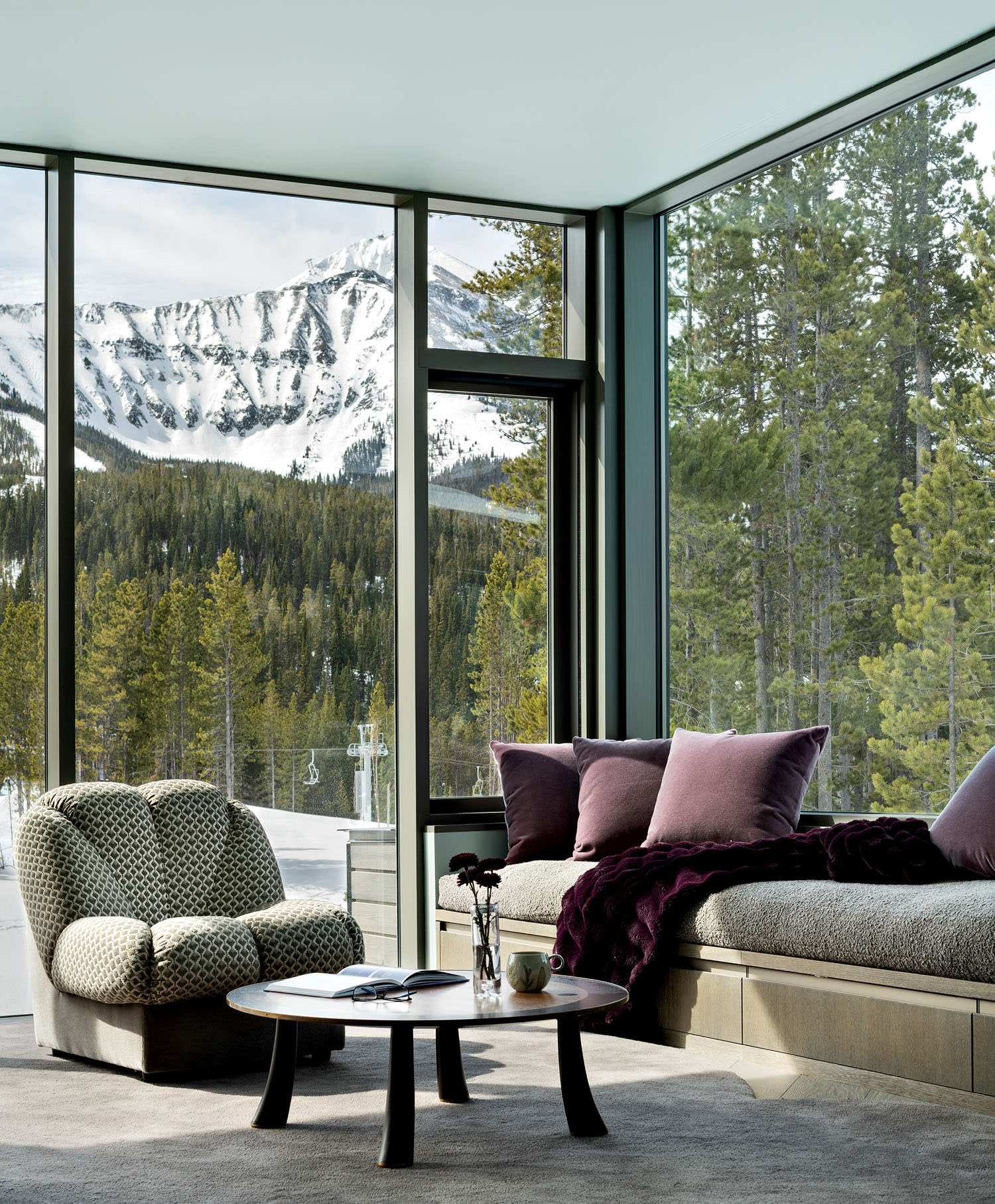 cozy seating area in the primary bedroom of a Big Sky home with views of snowy mountains outside