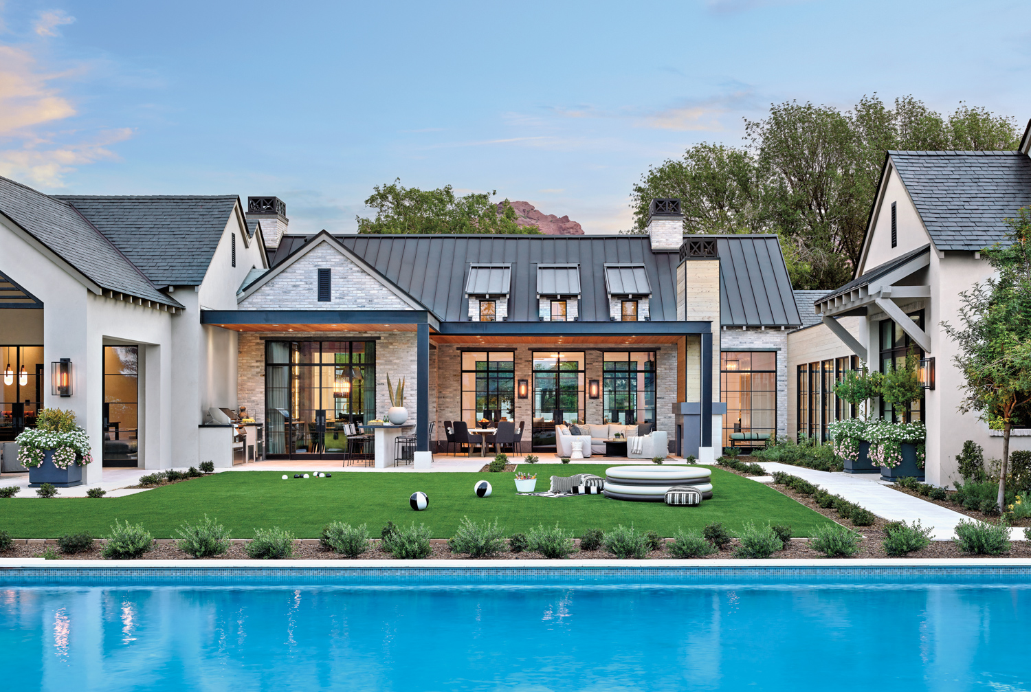 The backyard of a brick-and-stone modern farmhouse with a pool.