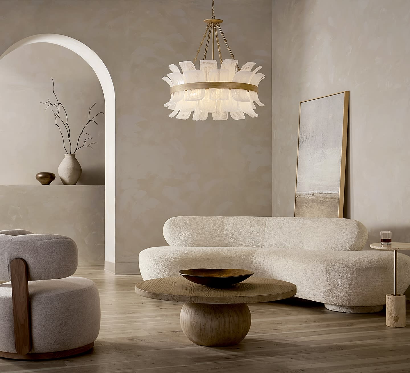 Minimalist living room with cream sofas, a round wooden table, and a modern chandelier. Neutral tones, art piece leaning on wall, calm ambiance.