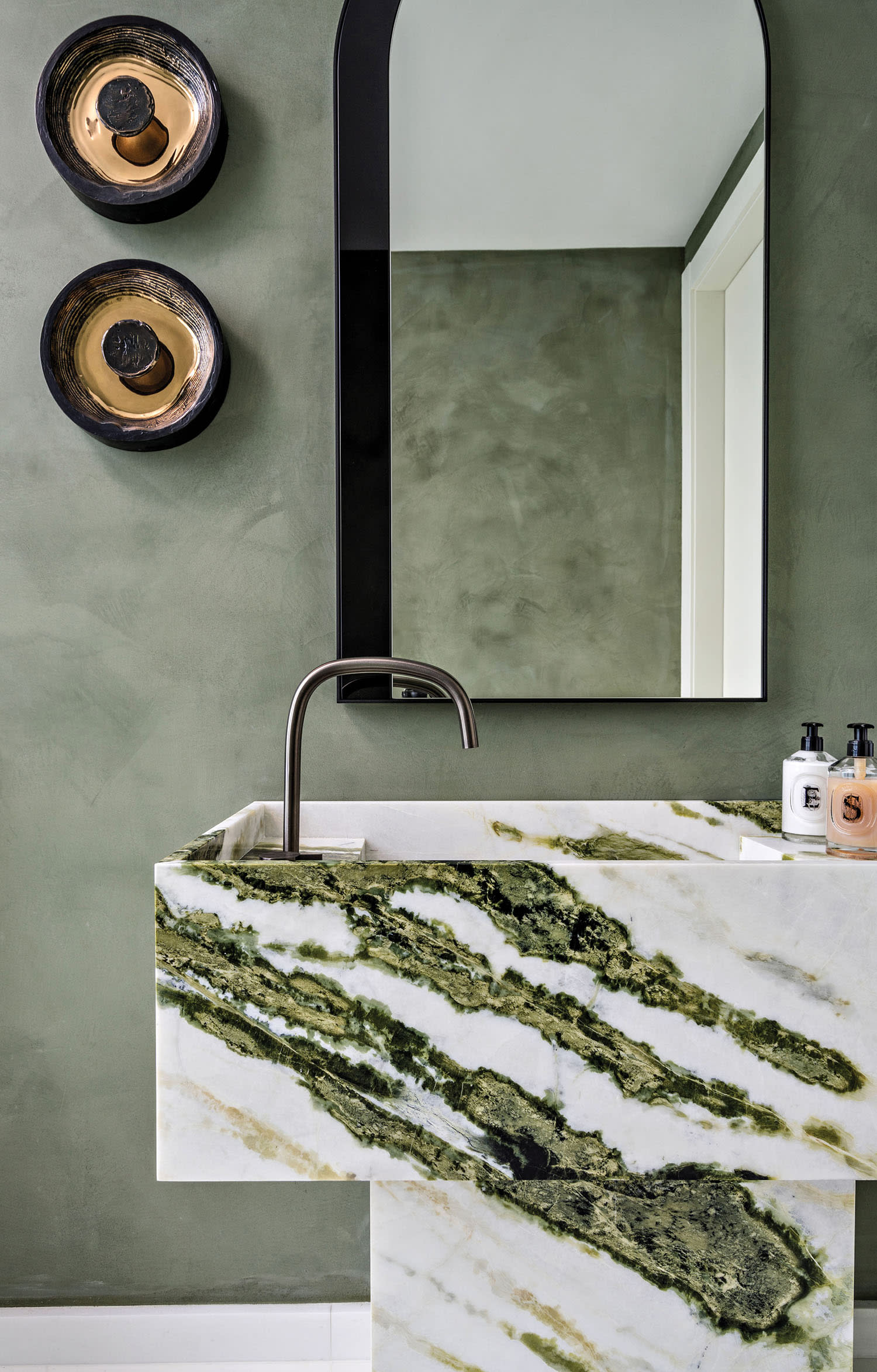 A white and green marble vanity in a bathroom with green walls.