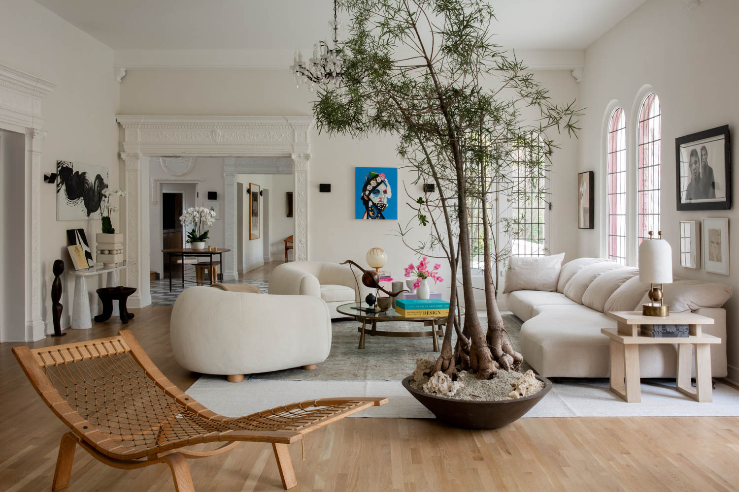 living room with tall trees growing in a planter next to white sofa and chairs