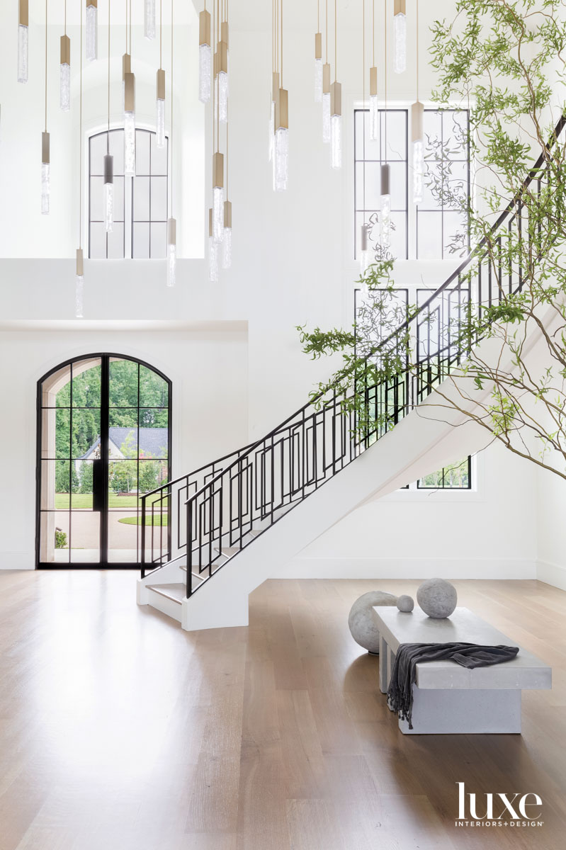 Vast entryway with spiral staircase, oversized chandelier and stone bench