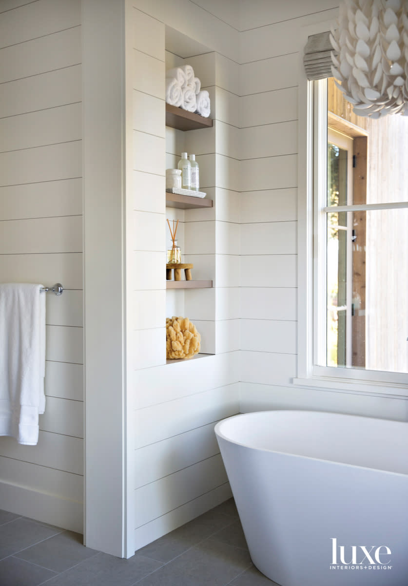 white bathroom with soaking tub and oak shelving