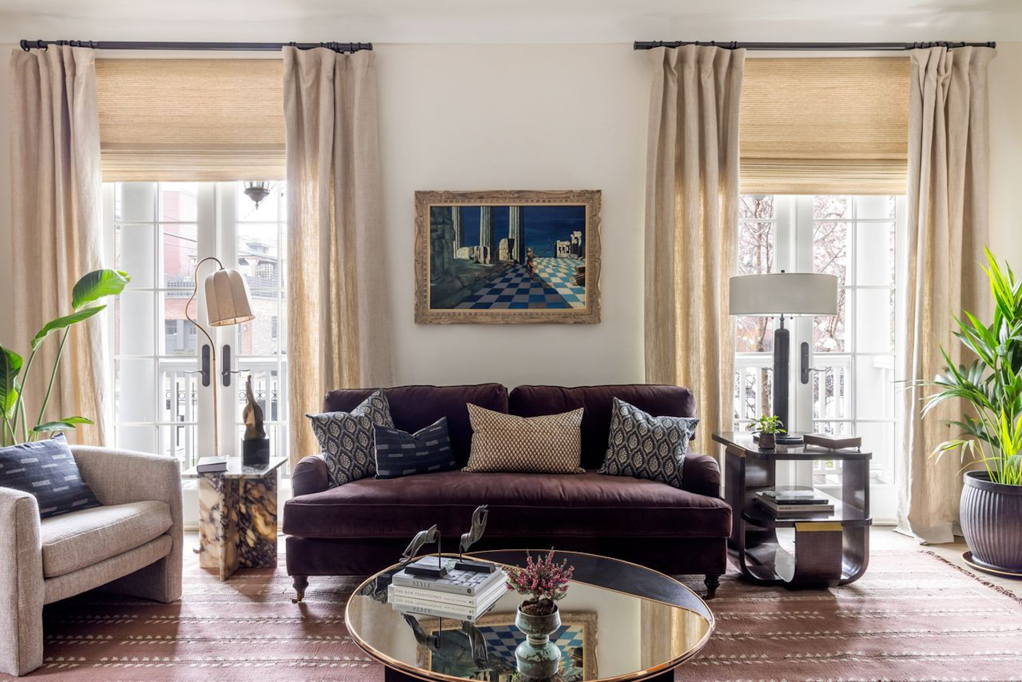 A tailored mix of textures and tones brings this sun-drenched living room to life. A velvet curved sofa anchors the space, joined by tailored drapery and sculptural accent pieces that reflect a collected, curated aesthetic.
