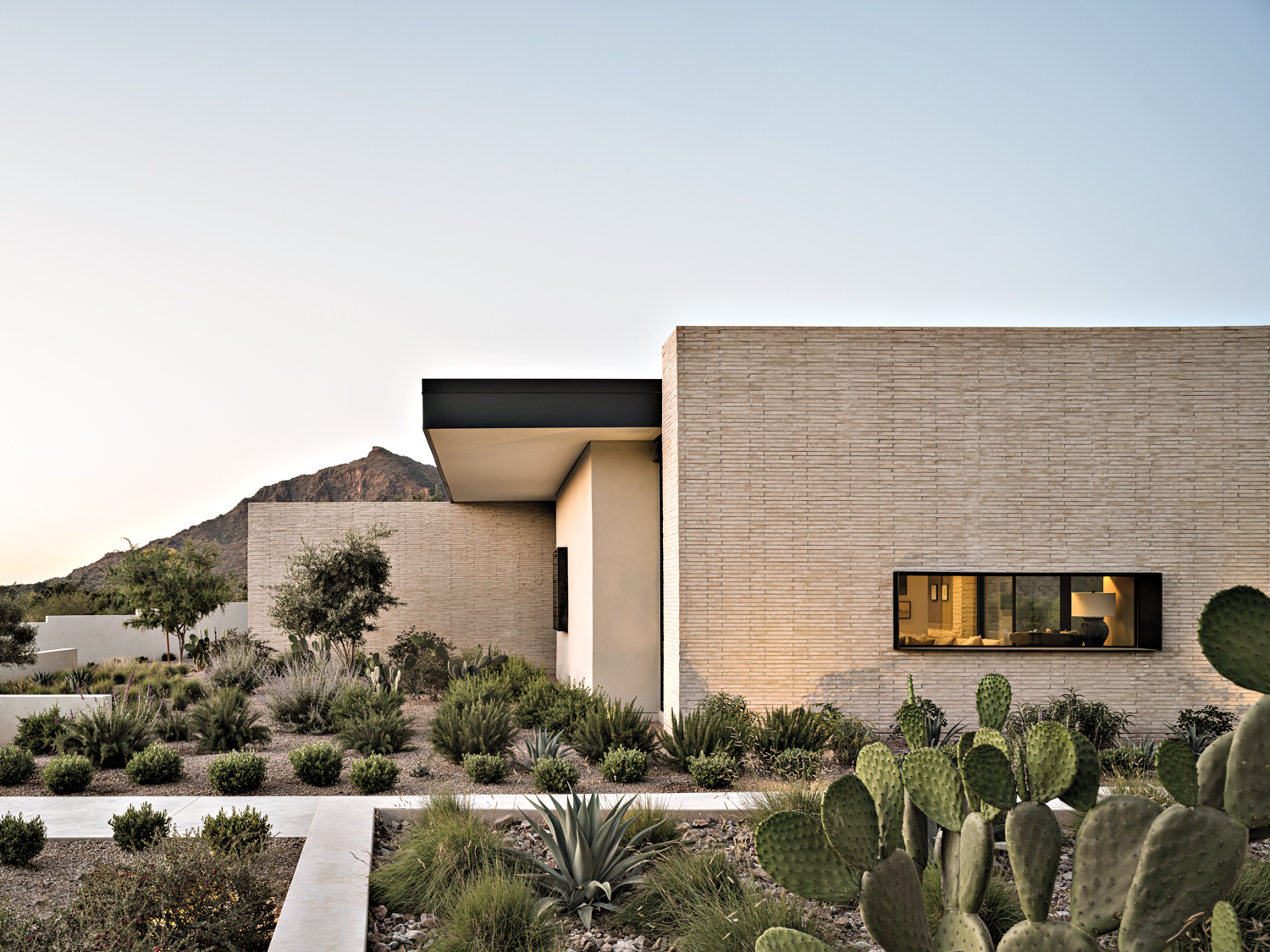 exterior of modern concrete brick house with desert plants in the yard