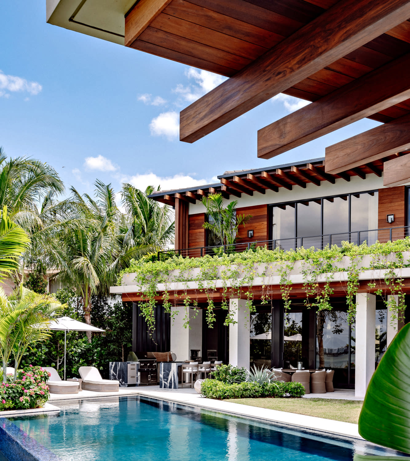 backyard with pool, seating, outdoor kitchen surrounded by plants