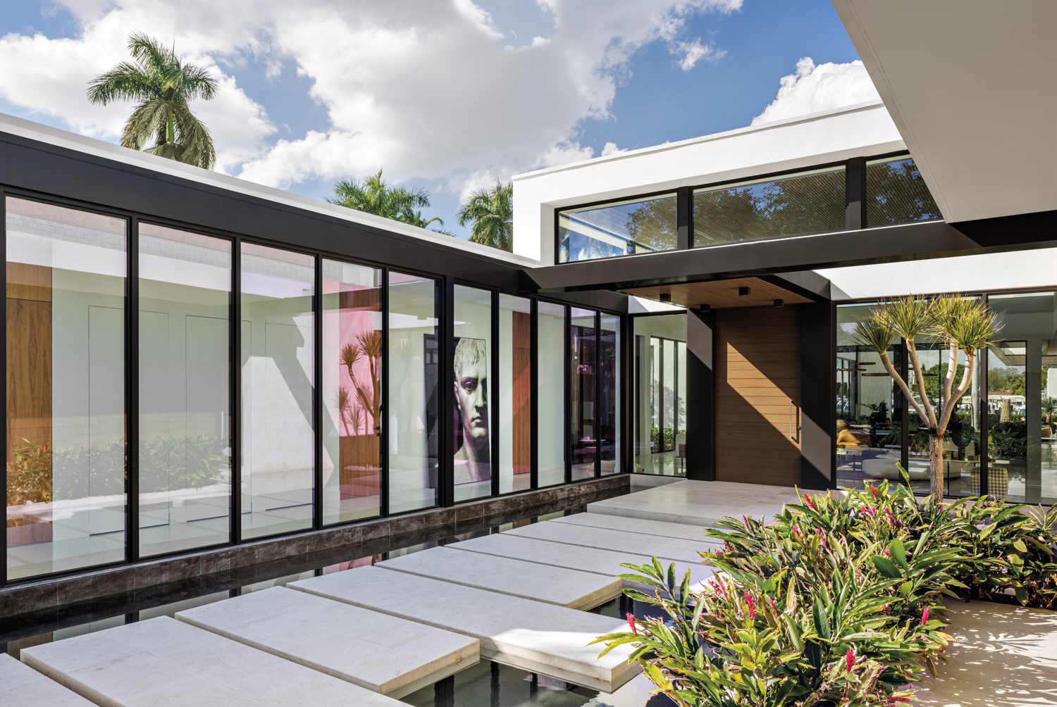 front exterior with glass walls and steps over water leading to front door