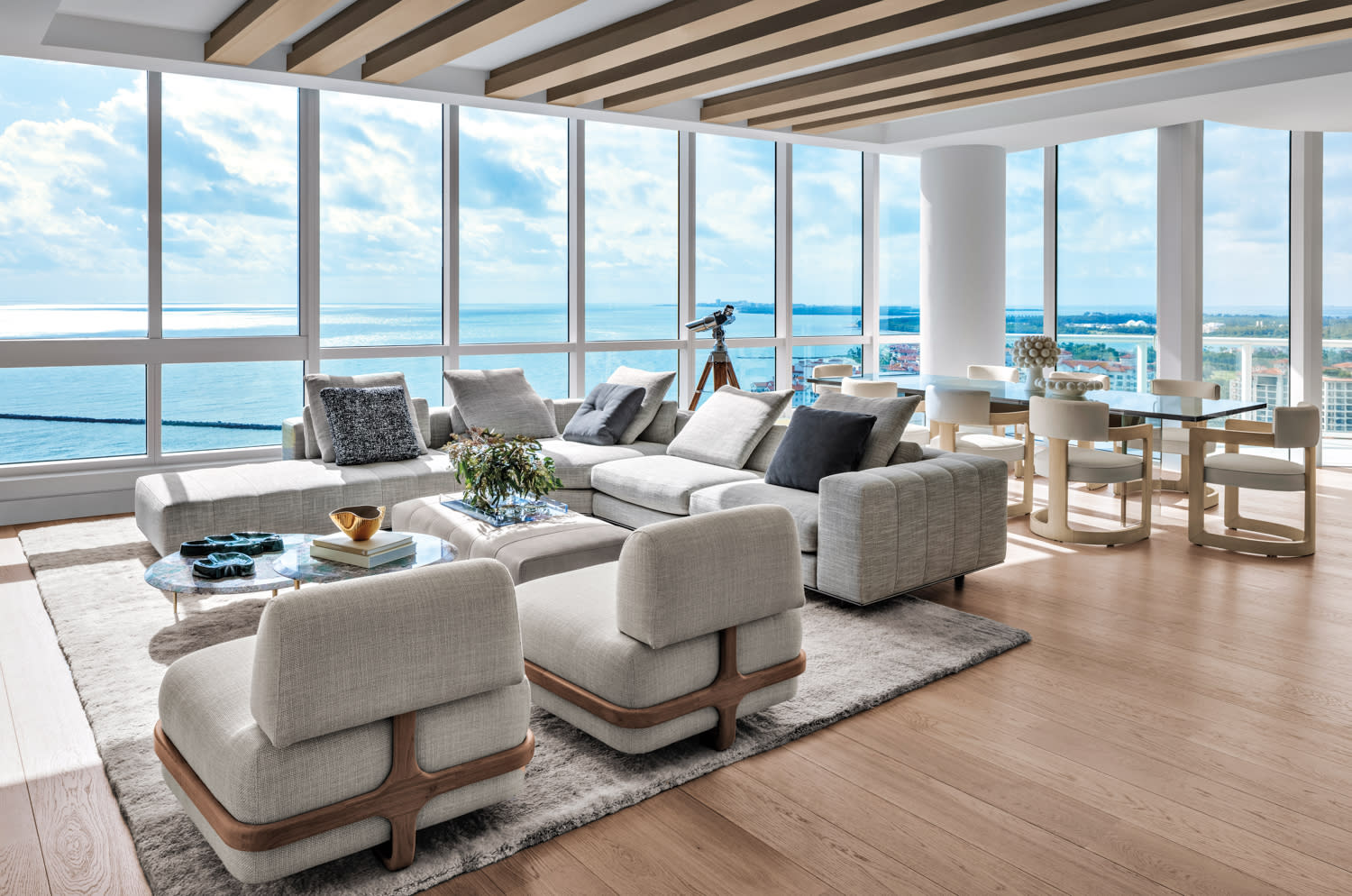 living area of high-rise with oceanfront views and low armchairs and sectional, and coffee tables