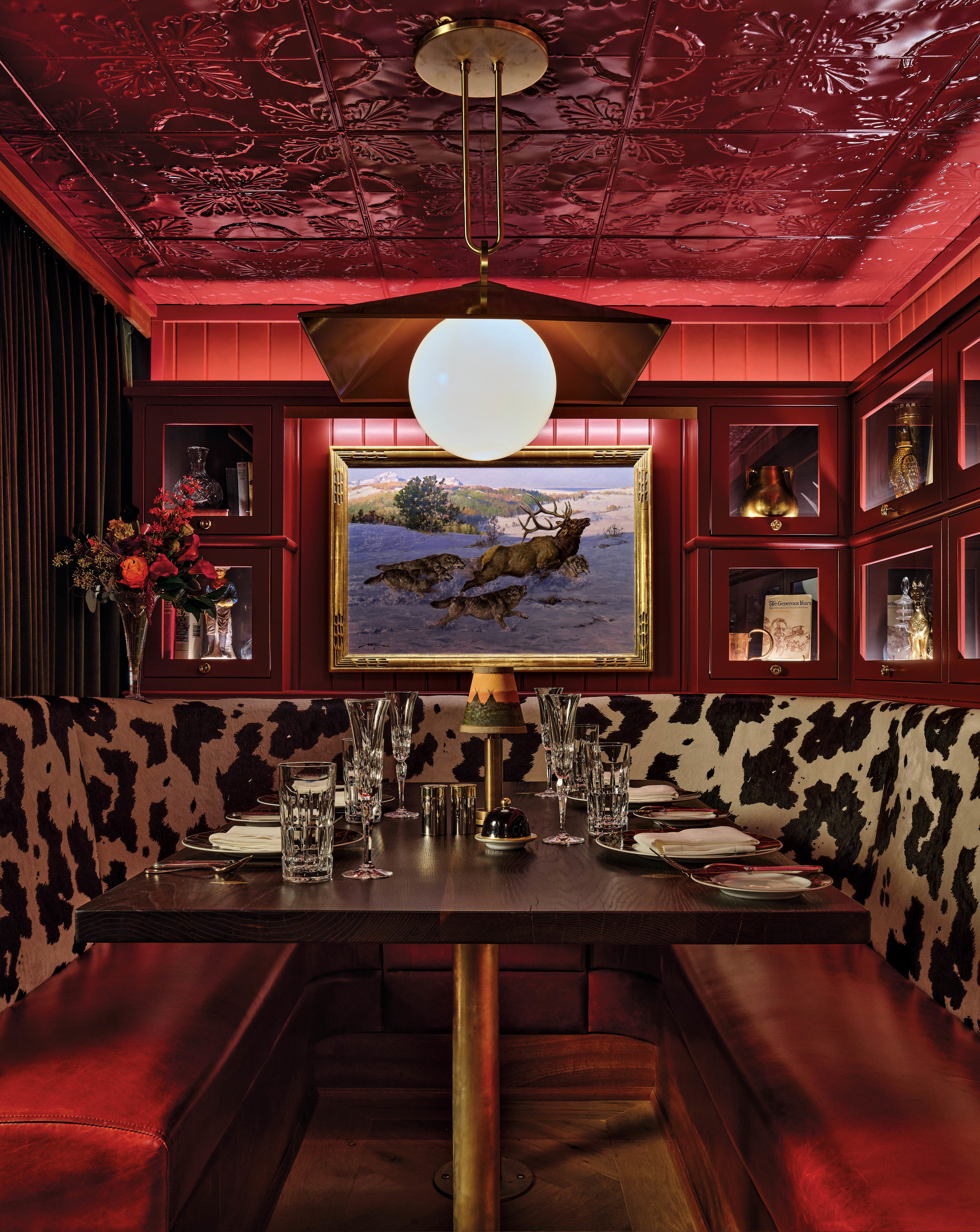 early 20th-century style bar with red walls and an animal print banquette