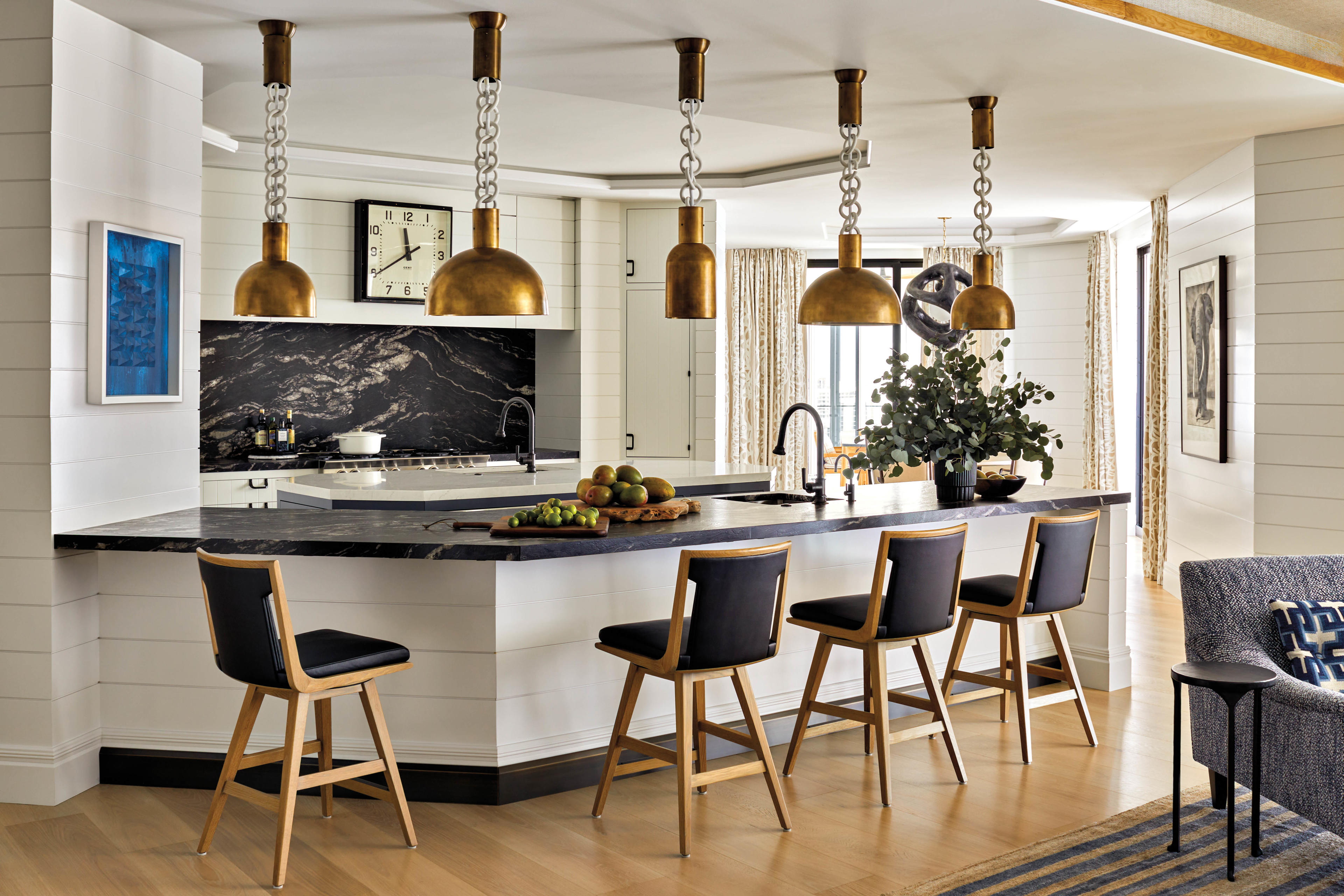 contemporary kitchen with gold pendants and black marble counters and backsplash