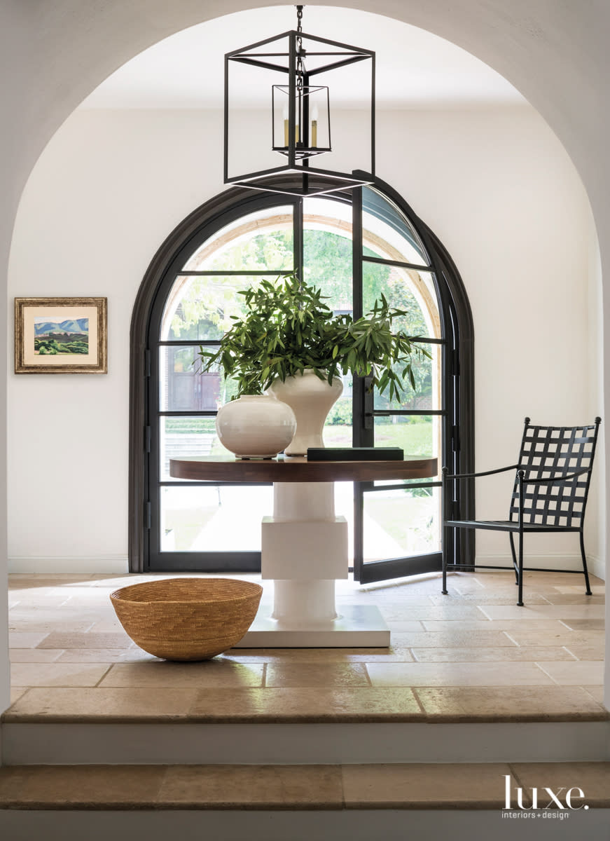 front door of windows featuring a table with a plant and chair at the door