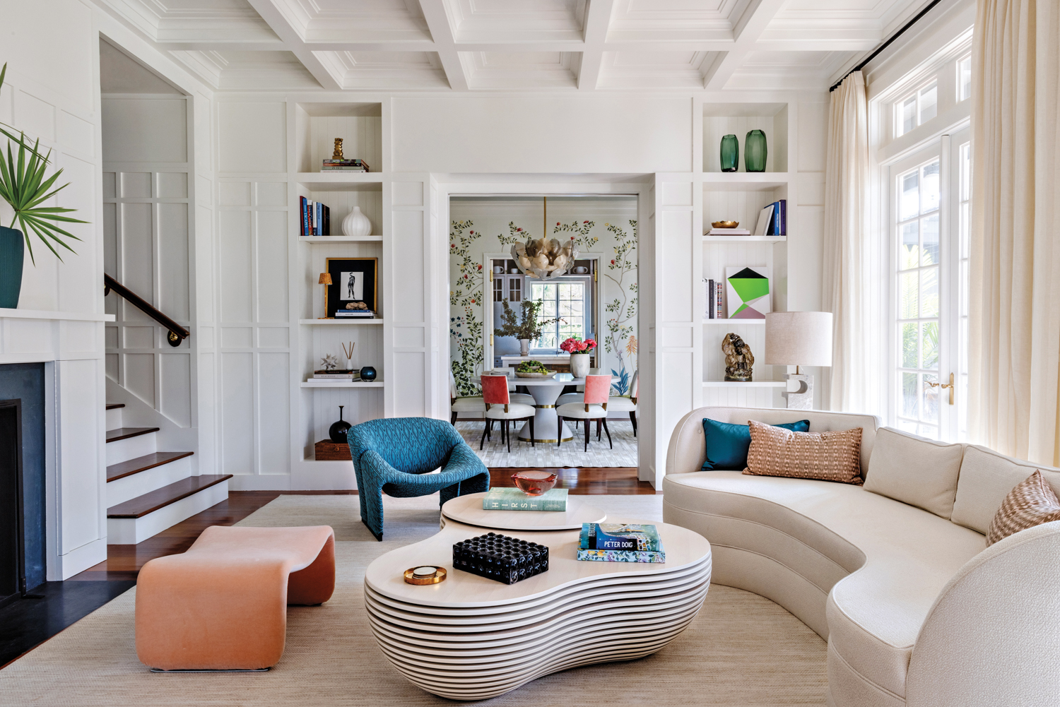 living area with white walls, curvy vintage furnishings, open shelving and sightline to dining room