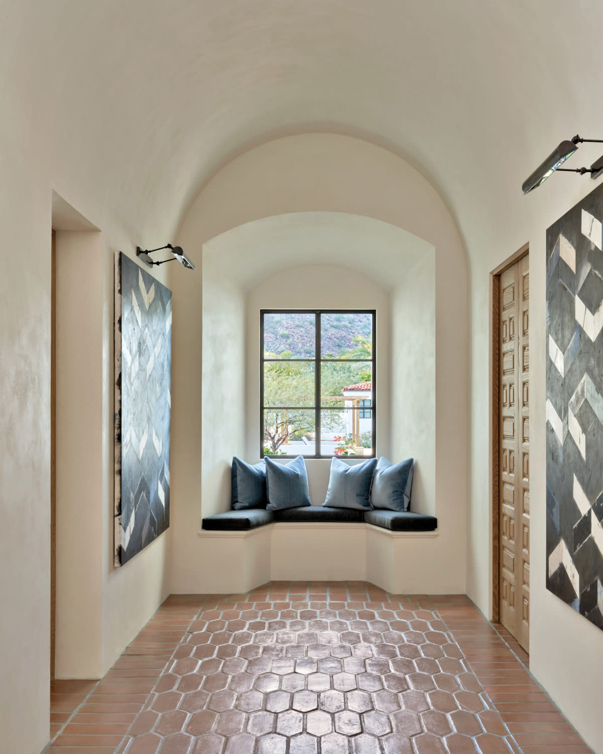 hallway with a cushioned window seat and two abstract paintings on either wall