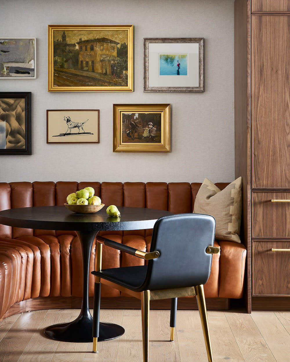 Leather banquette, black circular table and gallery wall.