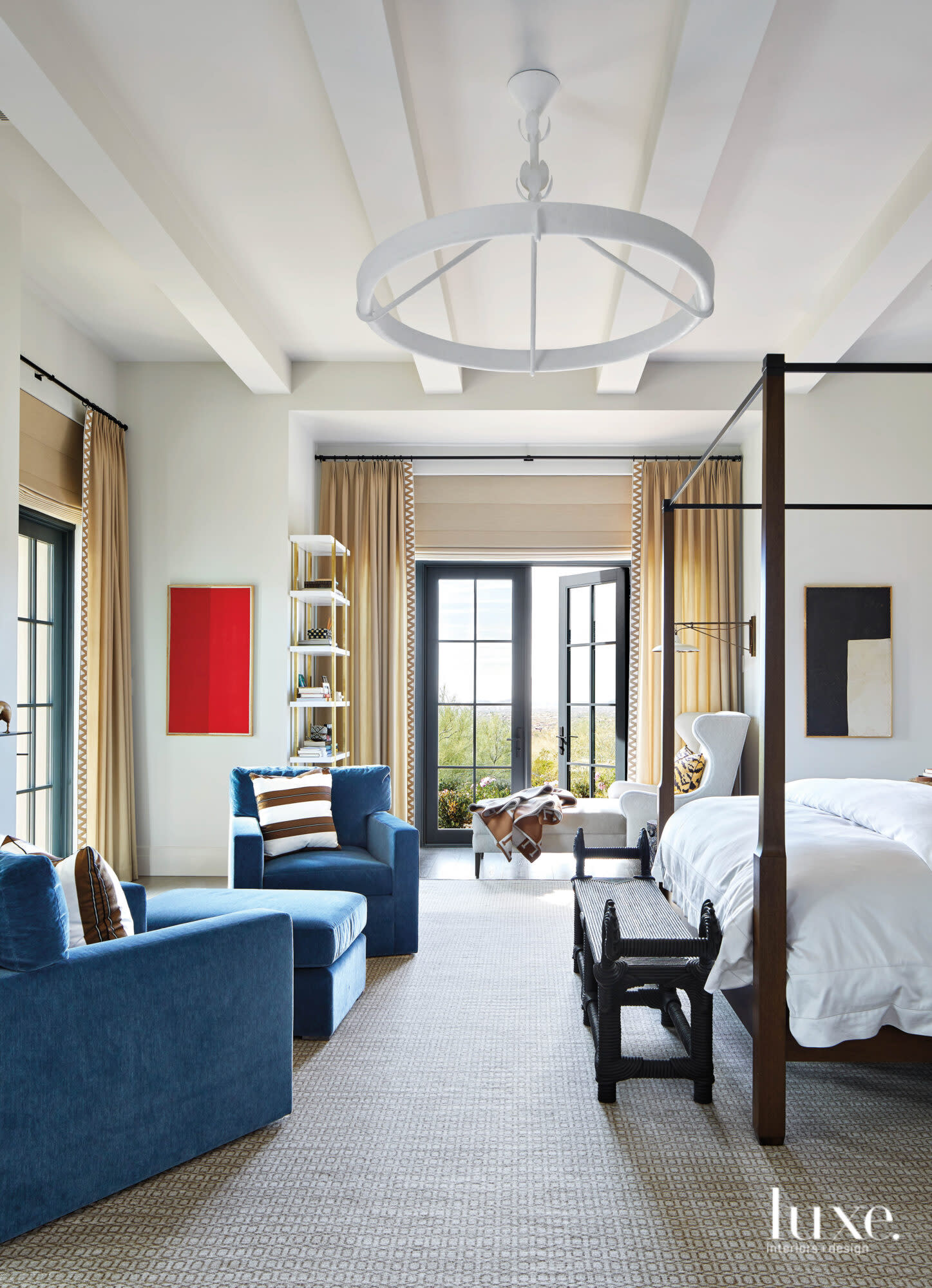 White finishes and two blue chairs sit in the master bedroom